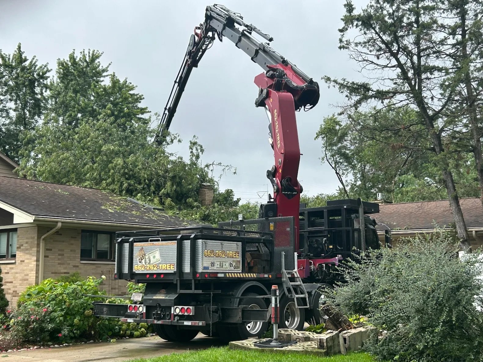 Garrison McKinney crane truck set up in a Fulton front yard, boom extended over a brick home
