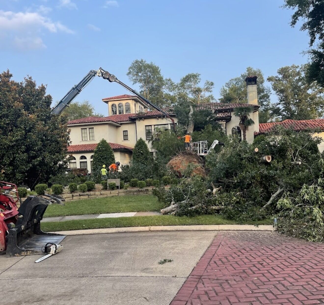 Garrison McKinney crane removing storm-damaged trees beside a historic home